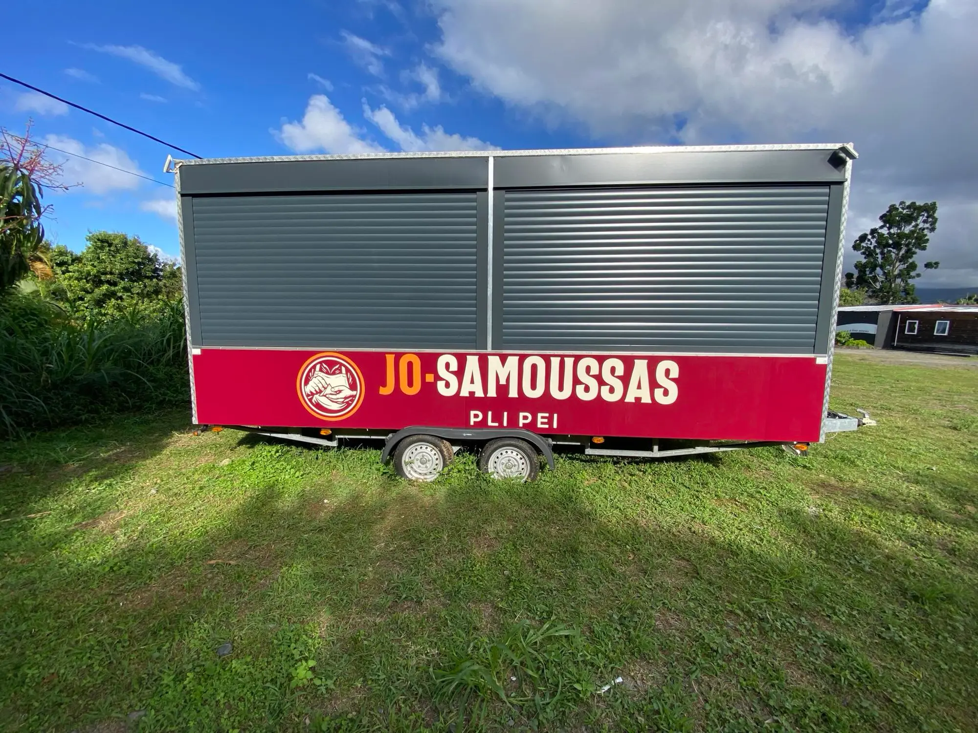 Roulotte Jo-Samoussas vue de profil, volets fermés, bandeau bordeaux au logo de la marque