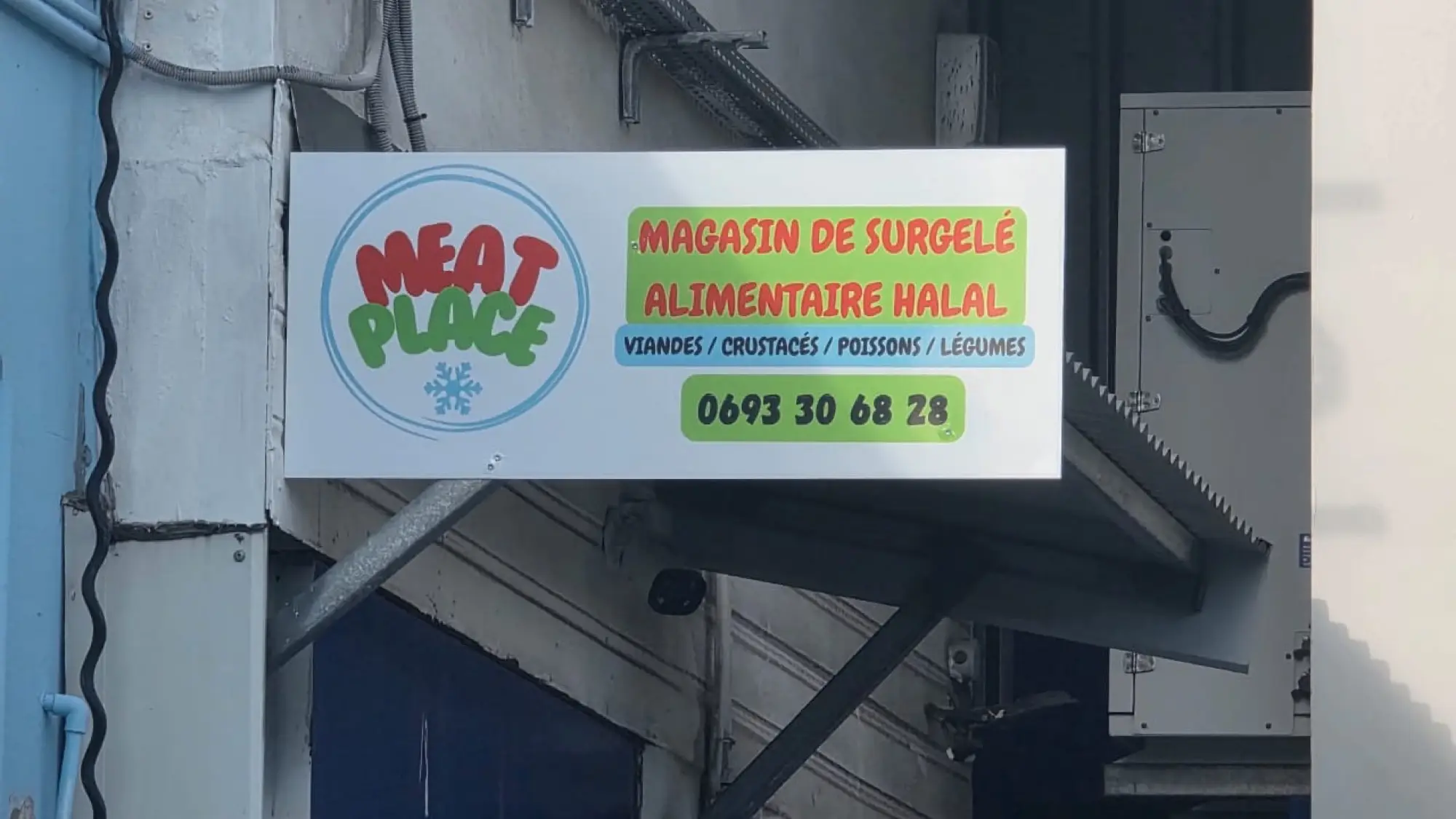 Enseigne Meat Place fixée en façade au-dessus d'un auvent, avec l'activité et le téléphone