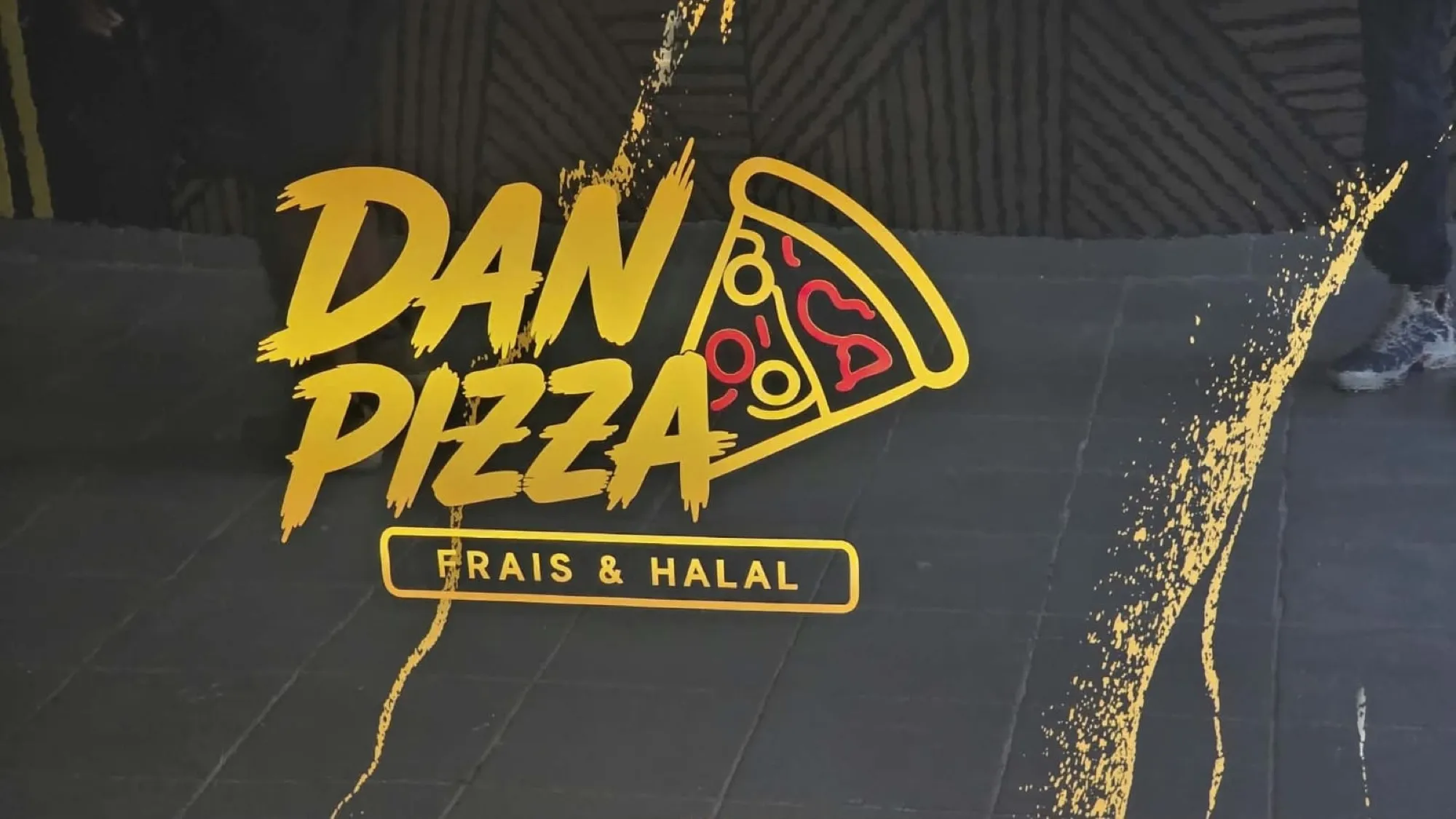 Comptoir de la pizzeria Dan Pizza habillé du logo en lettrage doré