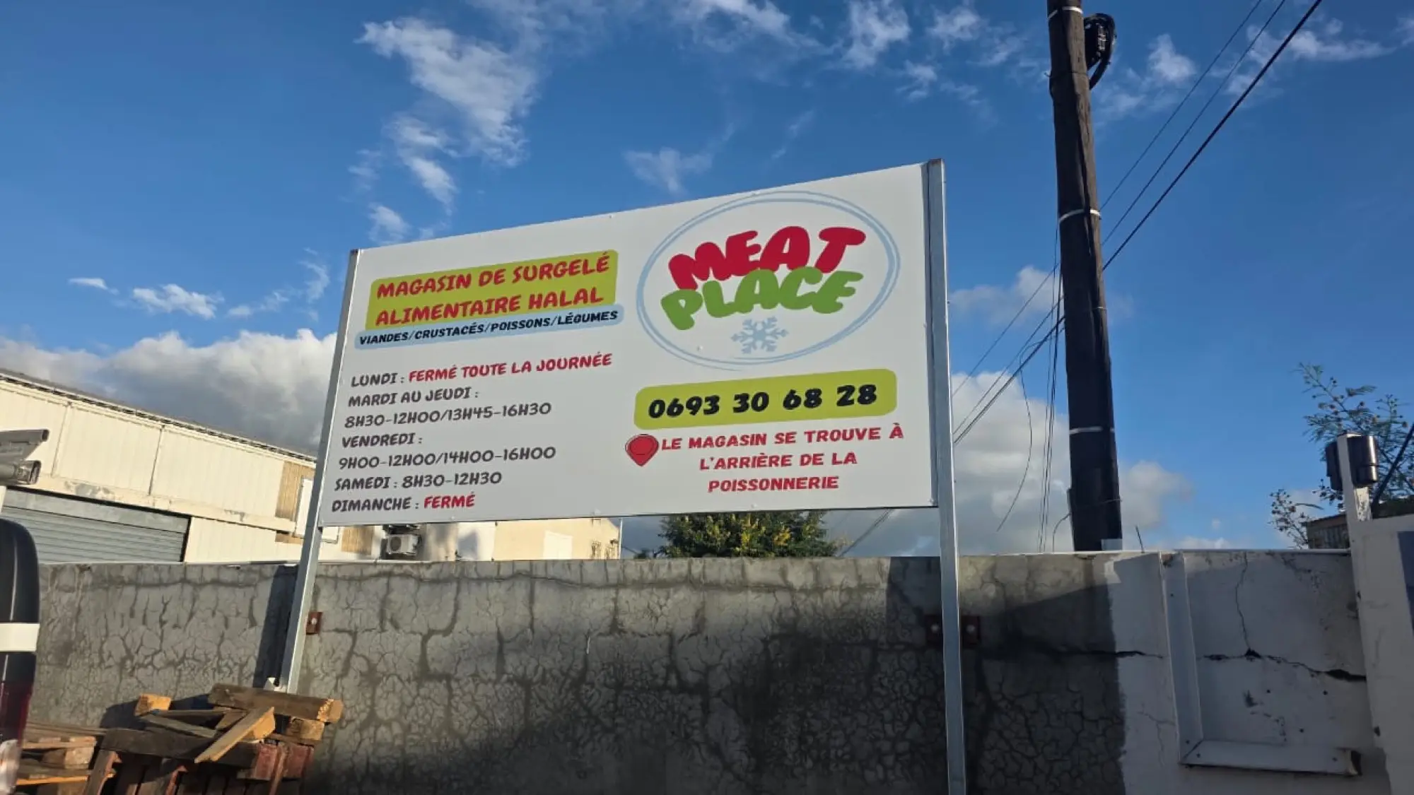 Grand panneau sur pieds Meat Place avec horaires, téléphone et indication d'accès, devant un mur